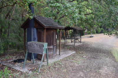 Sleepy Hollow KYBO and hand-washing station with fire ring in the background.